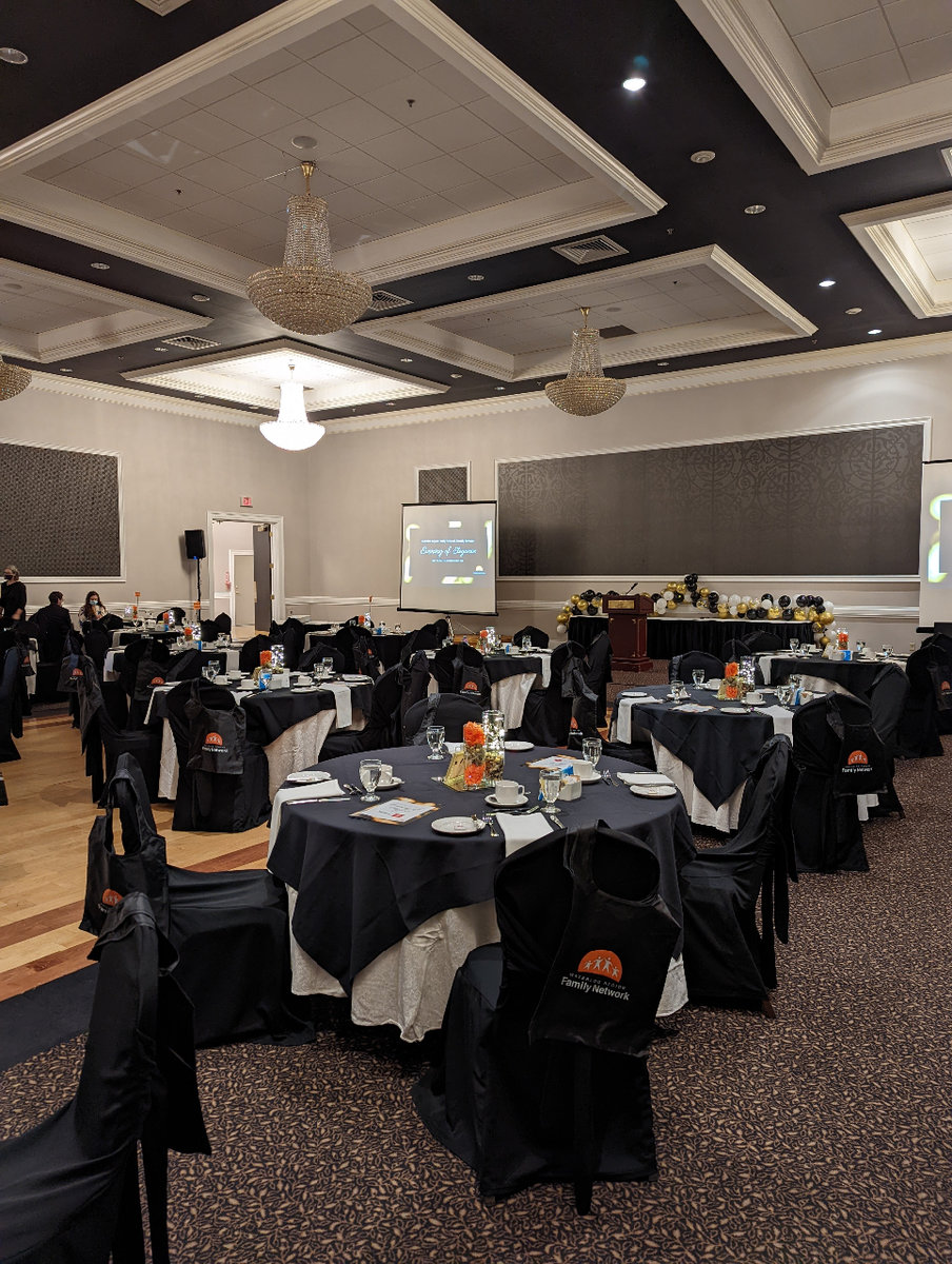 A large room of circular banquet tables with black table clothes.